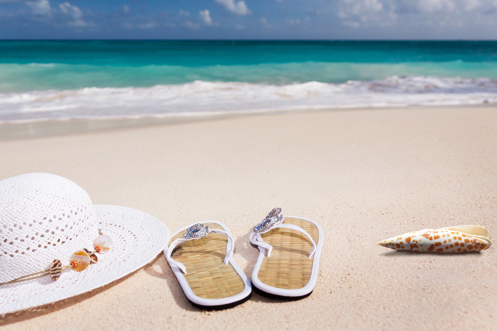 Beach with beach hat, shoes and seashell.